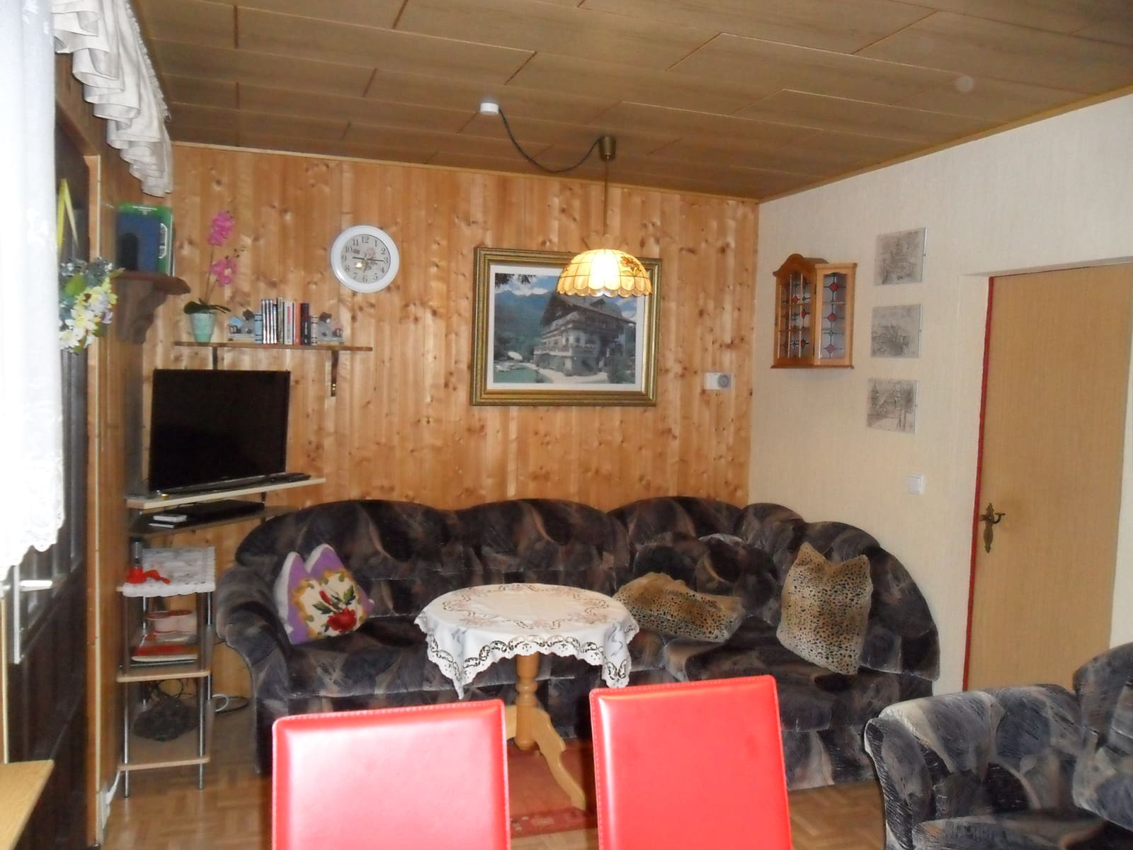 Wohnraum im Bungalow mit Polstergarnitur, Fernseher und heller Holzvertäfelung