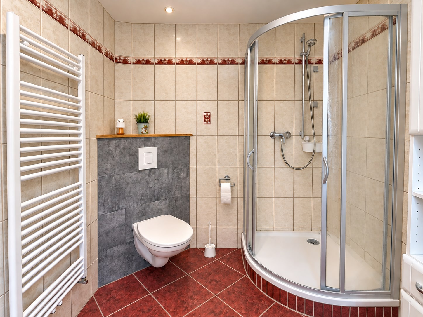 Erstes Bad der Ferienwohnung mit runder Dusche, WC und Handtuchheizkörper