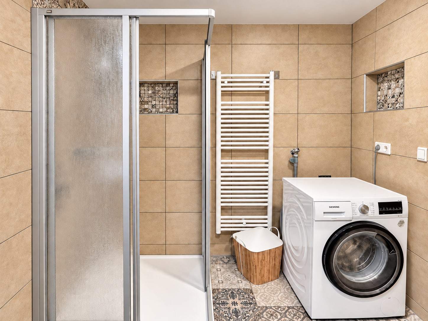 Zweites Bad der Ferienwohnung mit Dusche, Waschmaschine und gemusterten Bodenfliesen