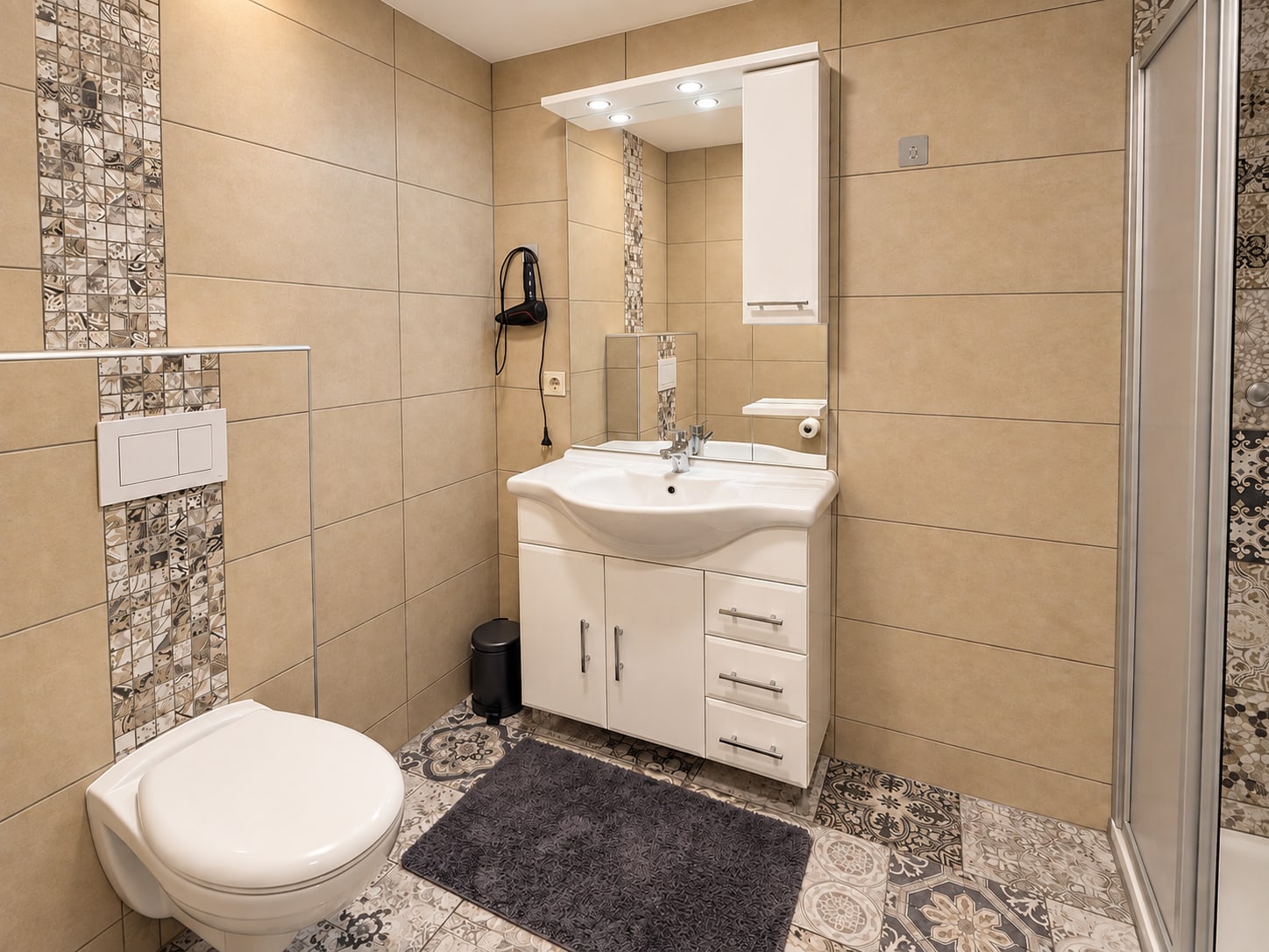Waschtisch und WC im zweiten Bad der Ferienwohnung mit beigefarbenen Wandfliesen