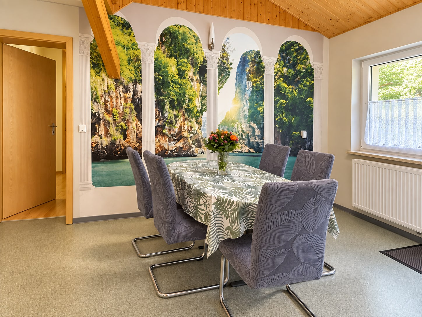 Essplatz der Ferienwohnung mit gepolsterten Stühlen und Wasserfallmotiv an der Wand