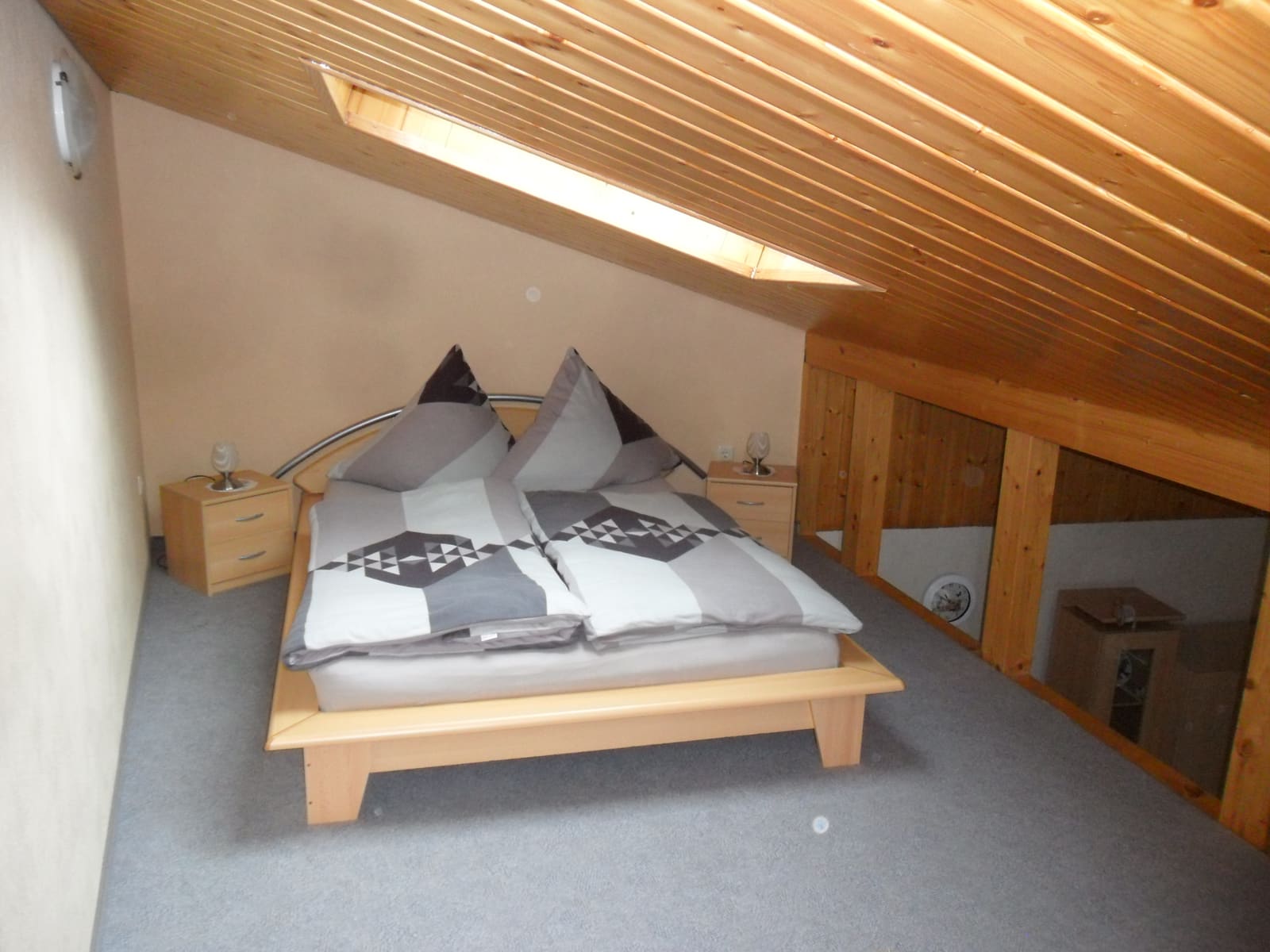 Schlafraum im Obergeschoss mit Doppelbett unter der Dachschräge und Holzdecke