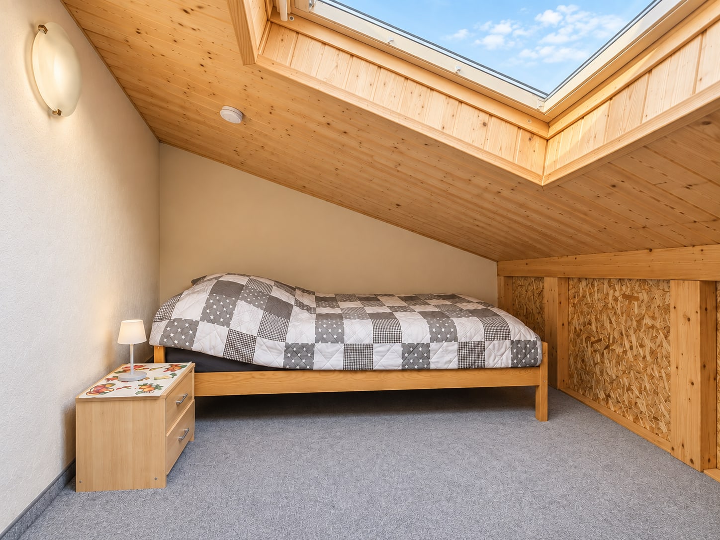 Schlafraum der Ferienwohnung unter der Dachschräge mit Bett und Dachfenster