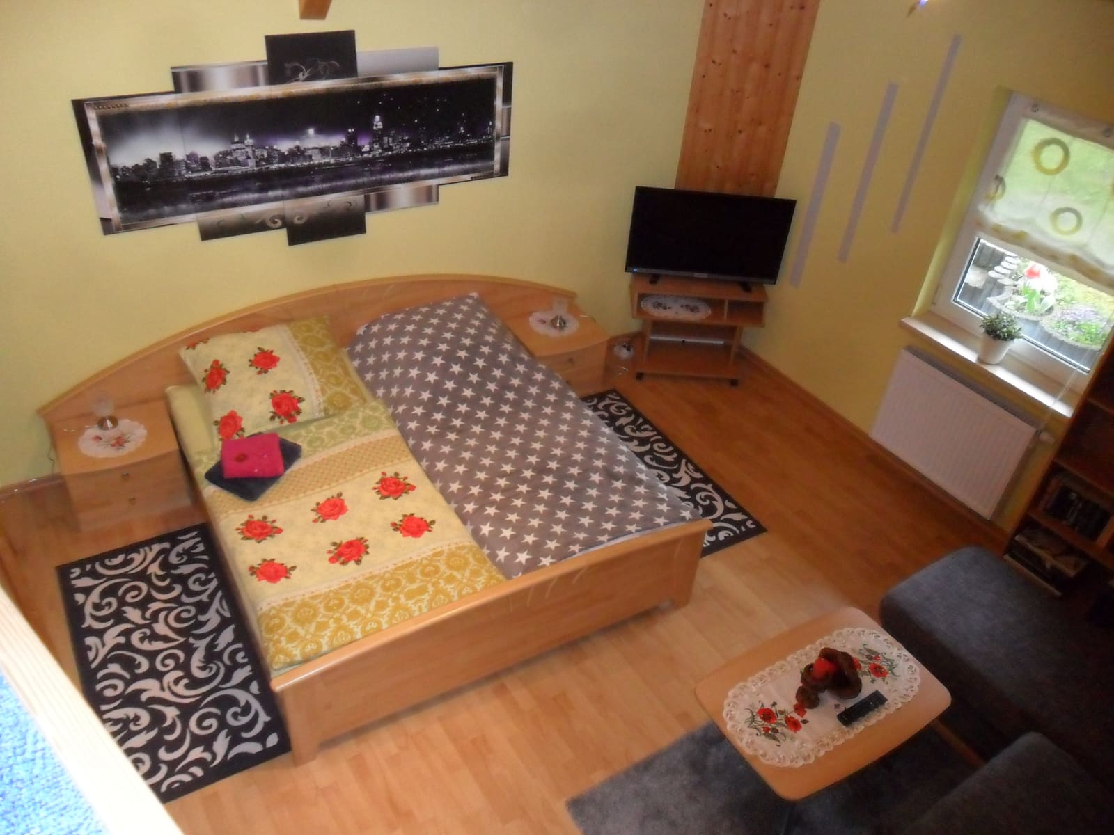 Schlafzimmer der Ferienwohnung mit Doppelbett aus hellem Holz und Fernseher