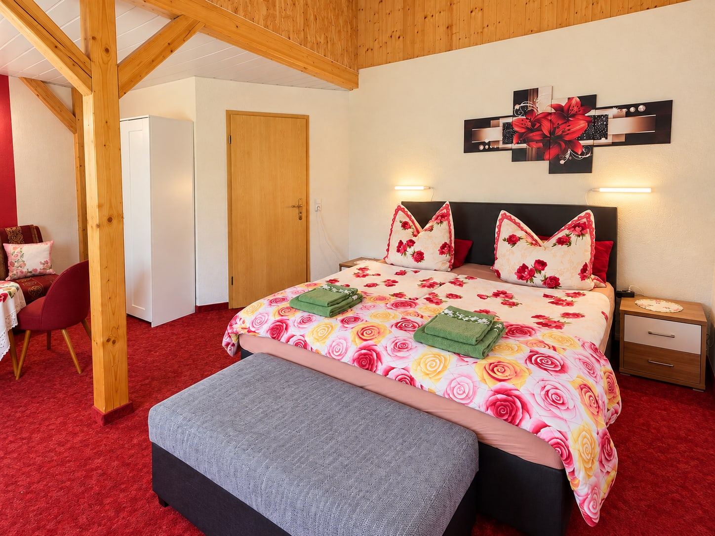 Doppelbett mit Rosenbettwäsche und grauer Sitzbank im zweiten Appartement der Ferienwohnung