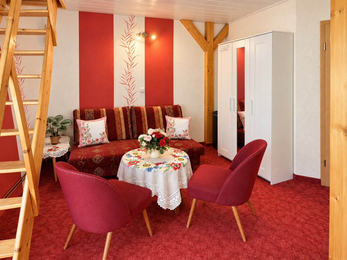 Rote Sitzecke im zweiten Appartement der Ferienwohnung neben der Treppe zum Schlafraum