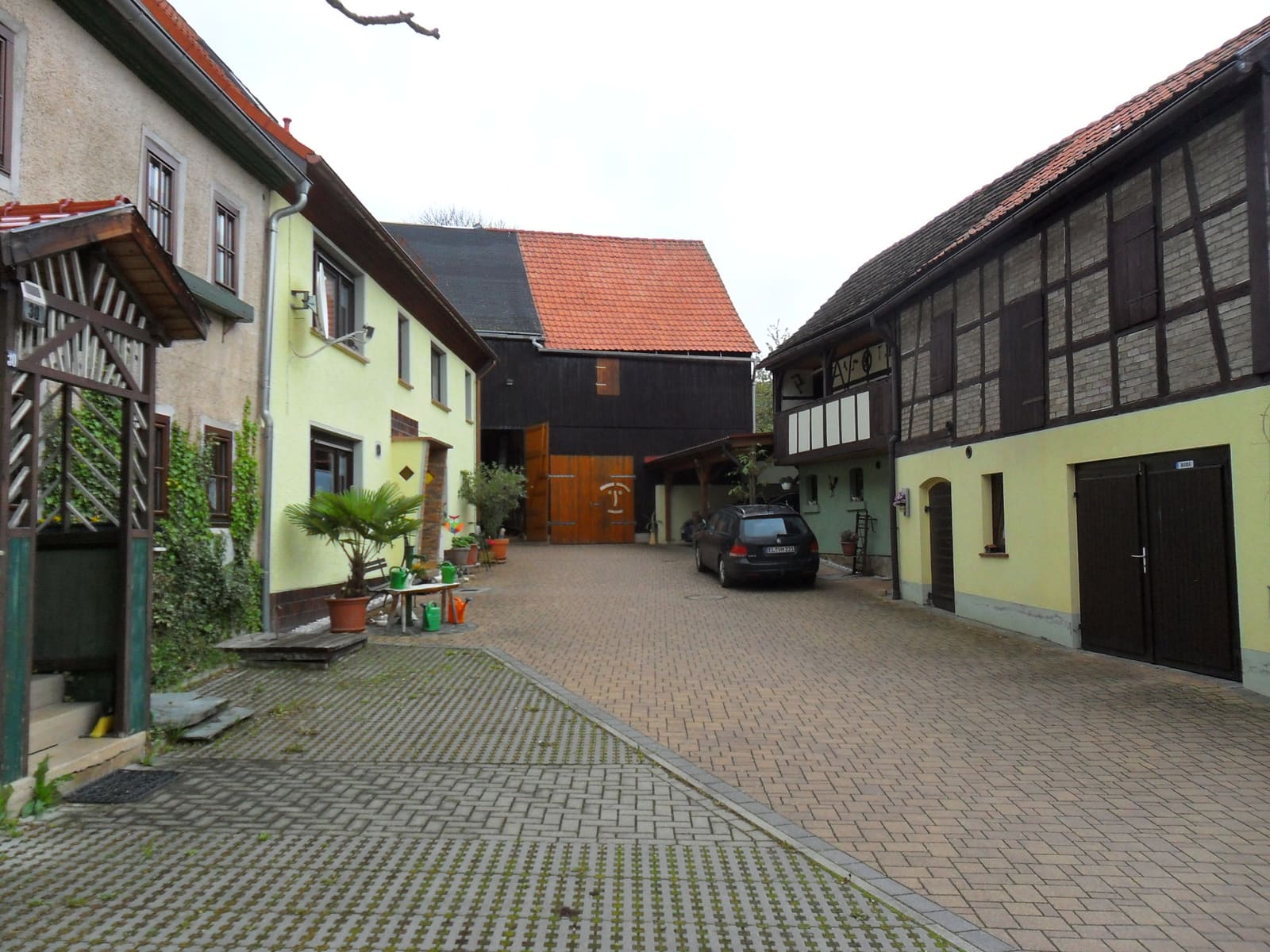 Gepflasterte Hofeinfahrt zwischen Wohnhaus und alter Fachwerkscheune