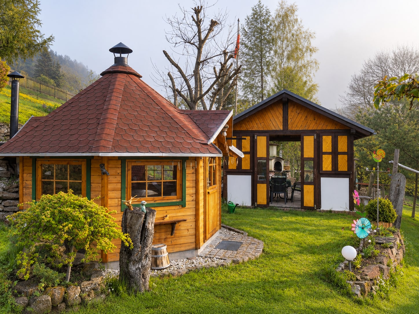 Grillkota und Gartenhaus an einem Nebelmorgen, im Hintergrund das Tal