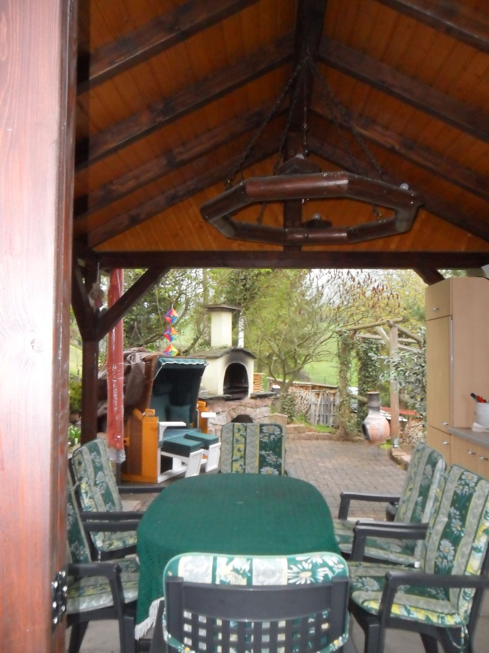 Überdachter Sitzplatz mit Gartenmöbeln und Blick in den Hof