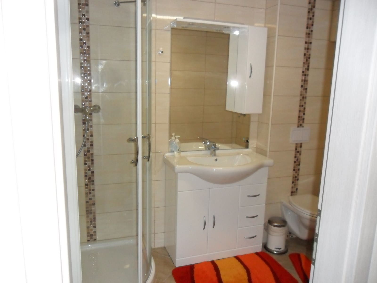 Modernes Bad der Single-Wohnung mit Dusche, Waschtisch und Spiegelschrank