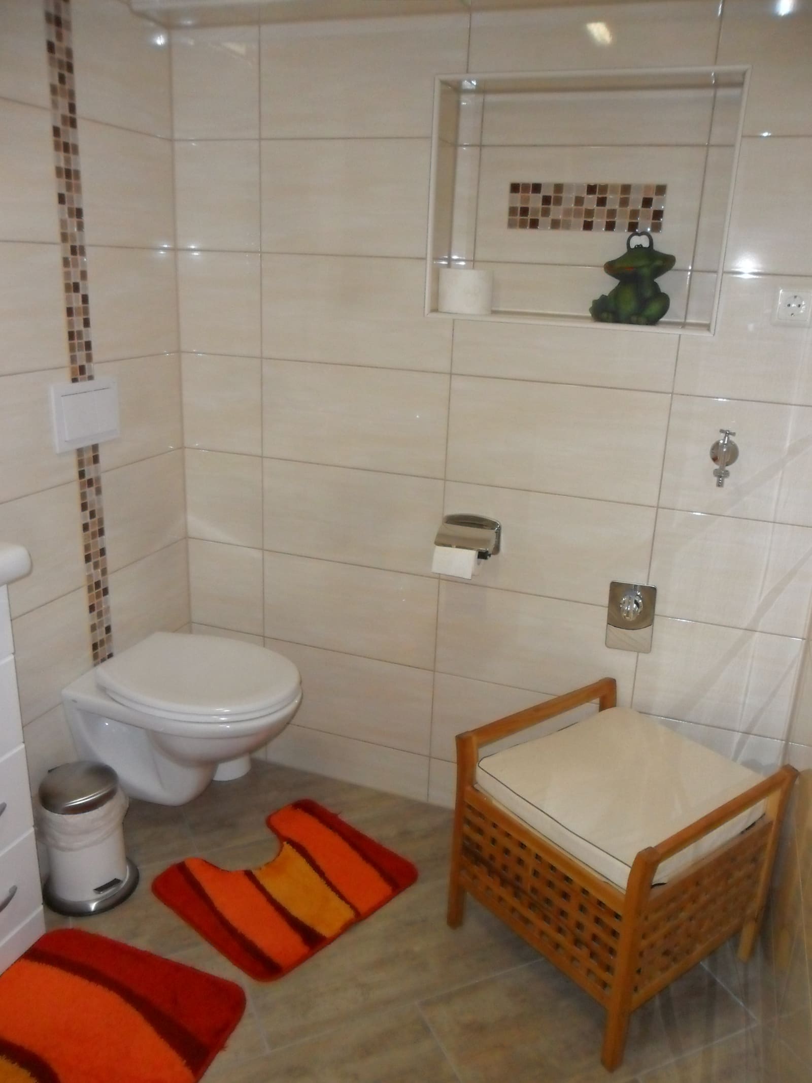 Hell gefliestes Bad der Single-Wohnung mit WC und Sitzbank