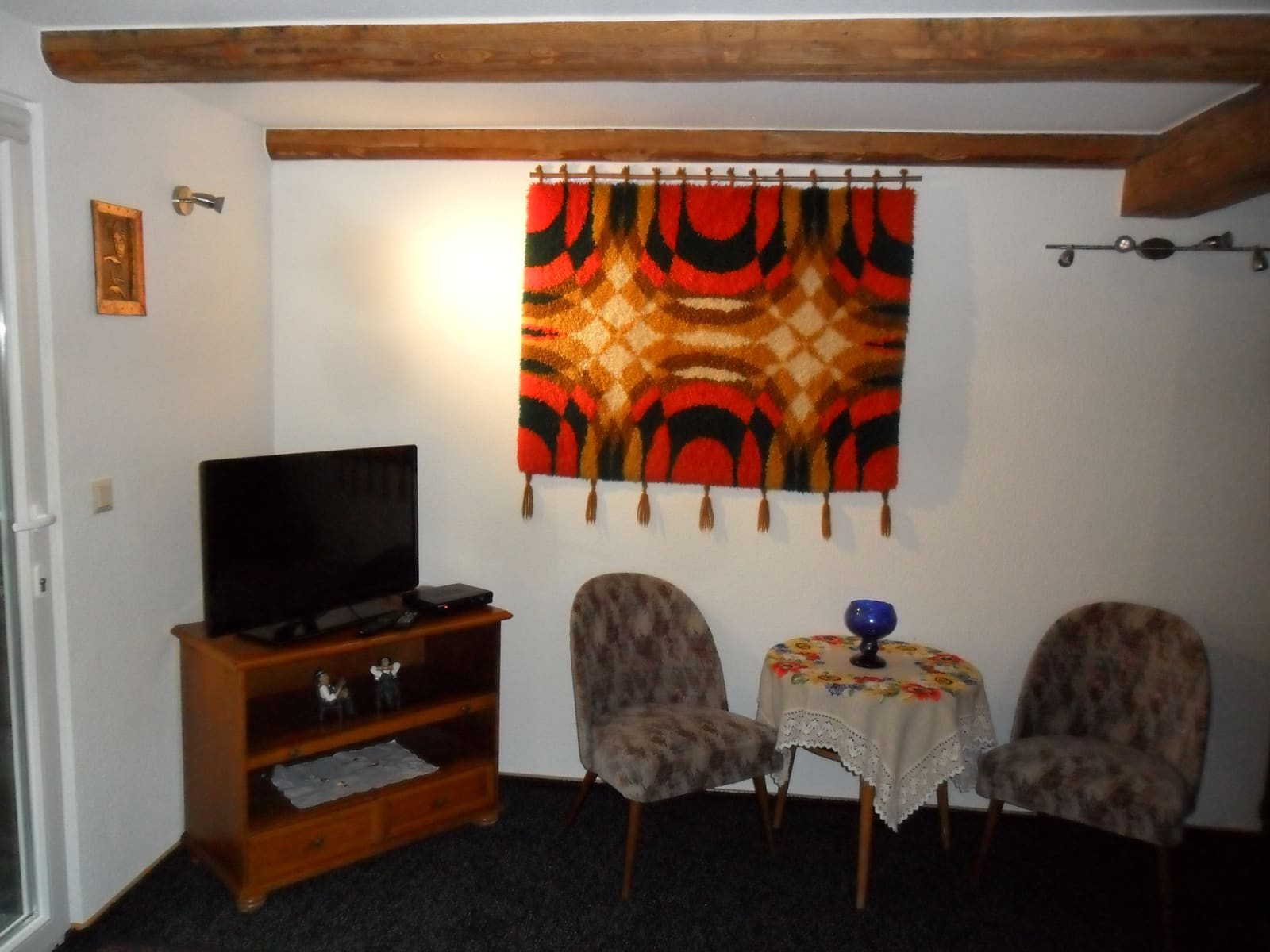 Wohnbereich der Single-Wohnung mit Fernseher, zwei Sesseln und kleinem Tisch